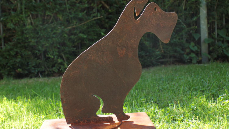 An oxidised steel dog urn standing in the garden.