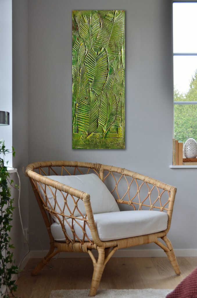 A painting of big leafs hanging on the wall of the corner of a grey room.