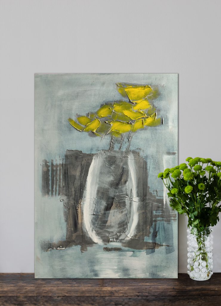 The yellow flower painting standing on the wooden floor, next to a flower vase.