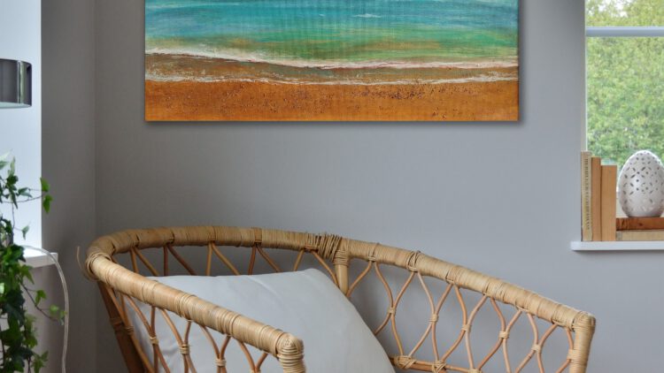 The painting of a beach hanging on the wall of the corner of a grey room.